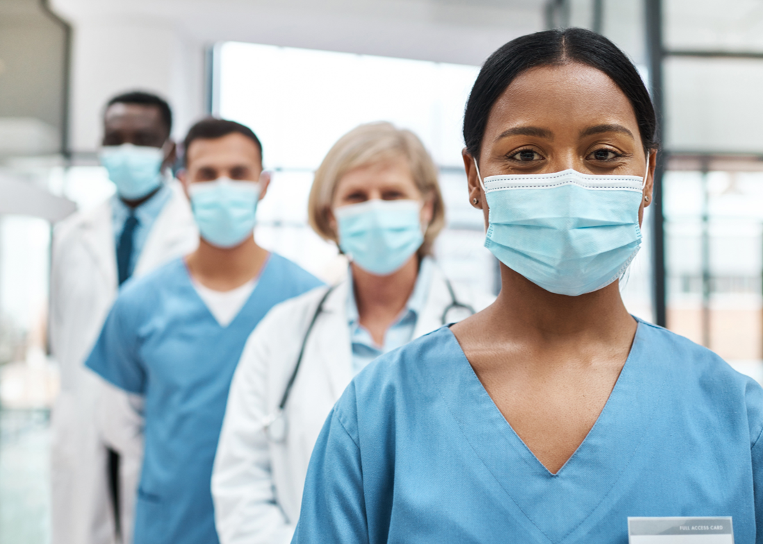 Healthcare workers wearing face masks and scrubs standing in a row