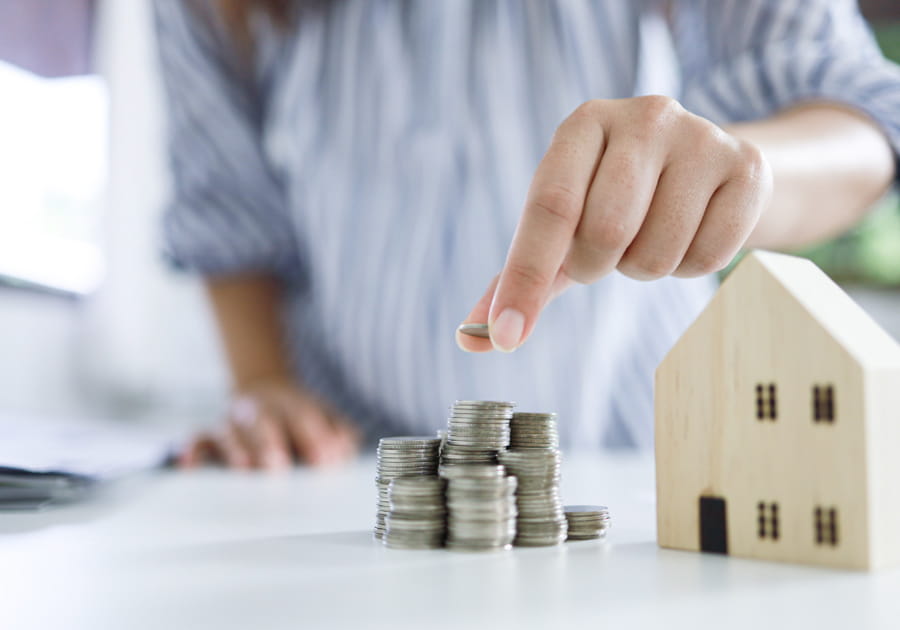 A person putting coins next to a wooden house